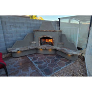 Kokomo Grills Santa Fe Outdoor Fireplace – Corner with 90-degree design, stucco base, stone top, and built-in seating with fire burning.
