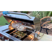 Kokomo Grills Laser Cut Grate 32In gas grill with stainless steel hood, interior lights, and rotisserie cooking whole chicken.