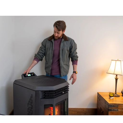 Man using a portable pellet stove in a room with a lamp and wooden side table.