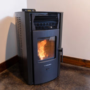 Black pellet stove with visible flames inside, mounted on a wall.