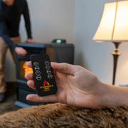 Hand holding a remote control with 'ComfortBilt' branding in a room with a fireplace and lamp.