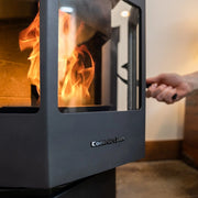 Person opening a modern fireplace with visible flames, featuring the brand 'ComfortBilt'.