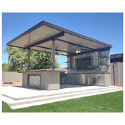 Kokomo Grills Outdoor Kitchen Montego Model BBQ Island with a built-in stainless steel grill, gray cabinets, stone backsplash, and covered roof.