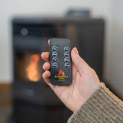 Hand holding a remote control with 'ComfortBilt' logo in front of a fireplace.