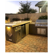 Kokomo Grills Baja/Fire L-Shaped BBQ Island with fire pit, 4 burner stainless steel grill, outdoor refrigerator, and porcelain countertop.