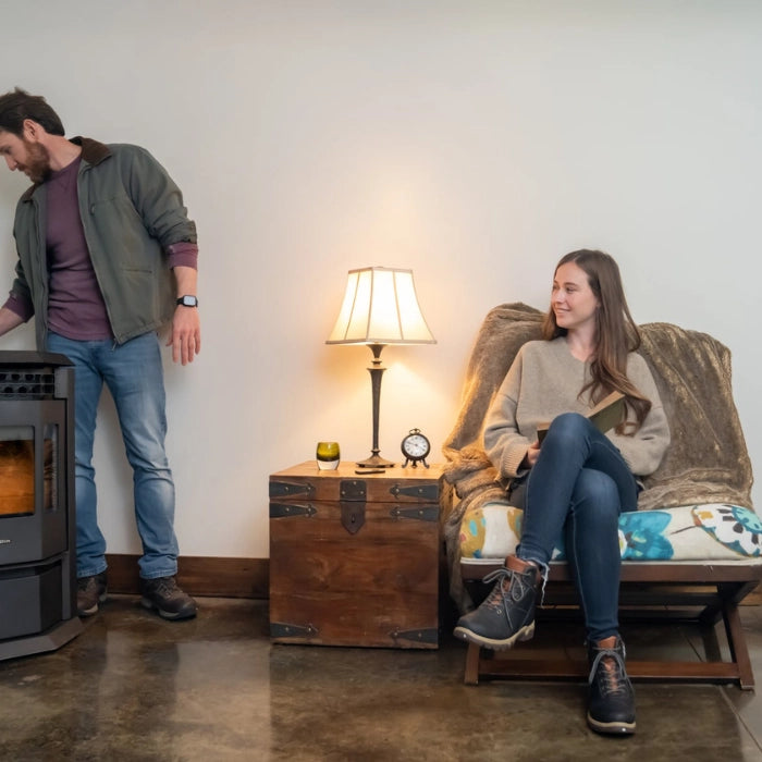 Man and woman in a cozy living room with a lamp and wooden chest.