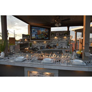 Kokomo Grills Best Outdoor Kitchen Bermuda BBQ Island with 4 burners, fire pit, TV, and stainless steel storage.