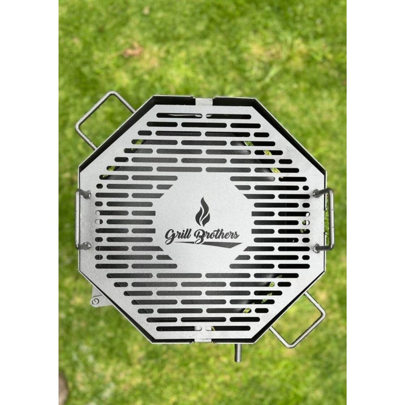 Grill Brothers Grill Travel portable stainless steel charcoal grill with folding grates and side handles on green grass background.