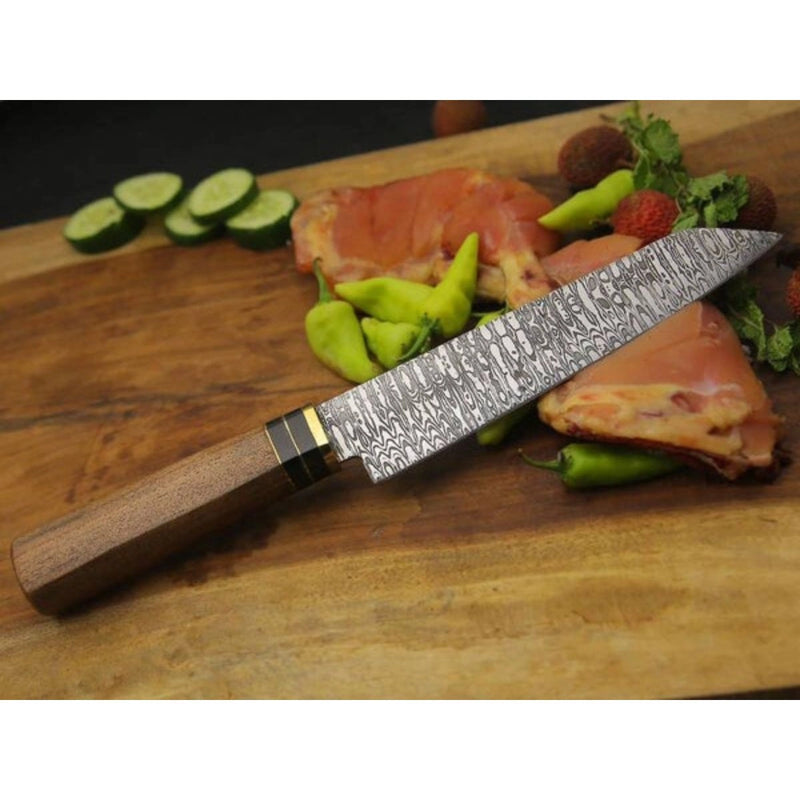 Grill Brothers KNIVES chef knife with patterned stainless steel blade and wooden ergonomic handle on a wooden cutting board.