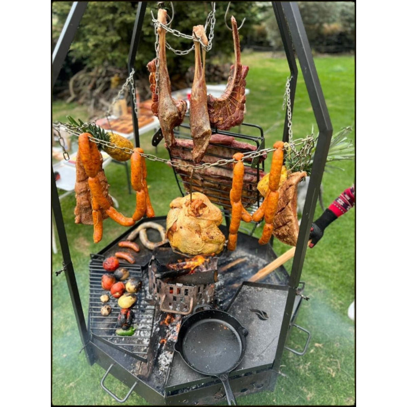 Grill Brothers Moster Doumo octagonal Argentine grill in black steel with hanging chains, adjustable cooking heights, and cast iron skillet.