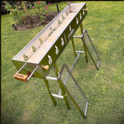 Grill Brothers Robatta freestanding charcoal grill with stainless steel body, decorative side cutouts, removable legs, and dual grilling racks.