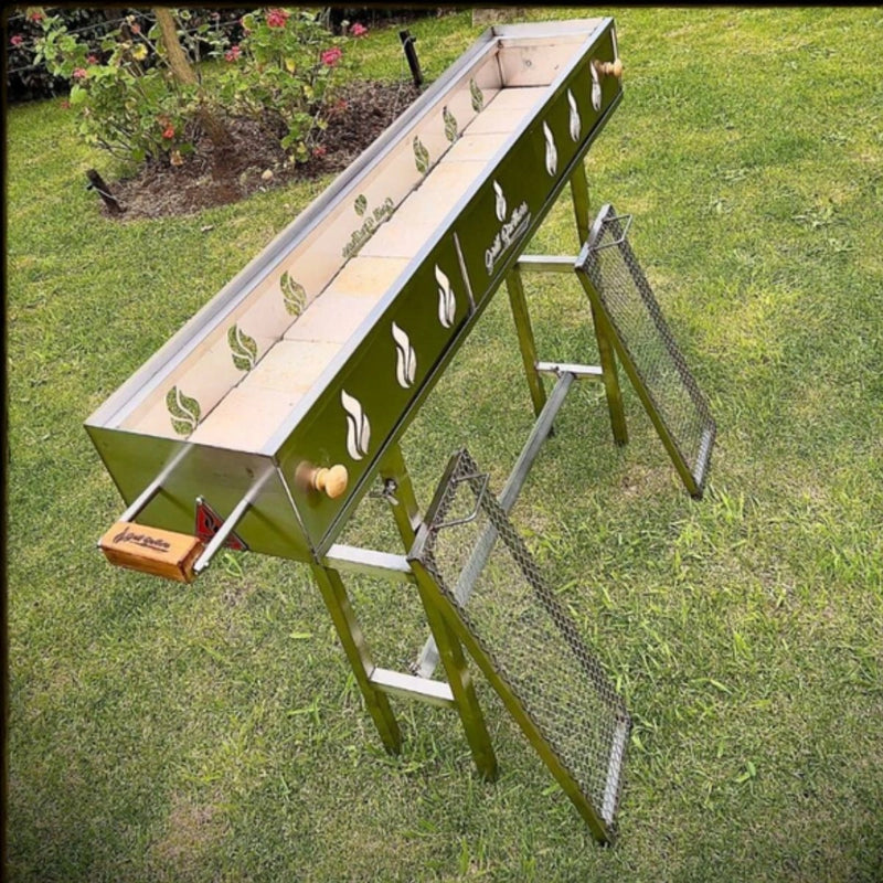 Grill Brothers Robatta freestanding charcoal grill with stainless steel body, decorative side cutouts, removable legs, and dual grilling racks.