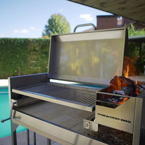 Tagwood BBQ Freestanding Argentine Santa Maria Grill with 304 stainless steel, 4 grilling areas, gaucho-style brasero firebox, and wood fire flames.