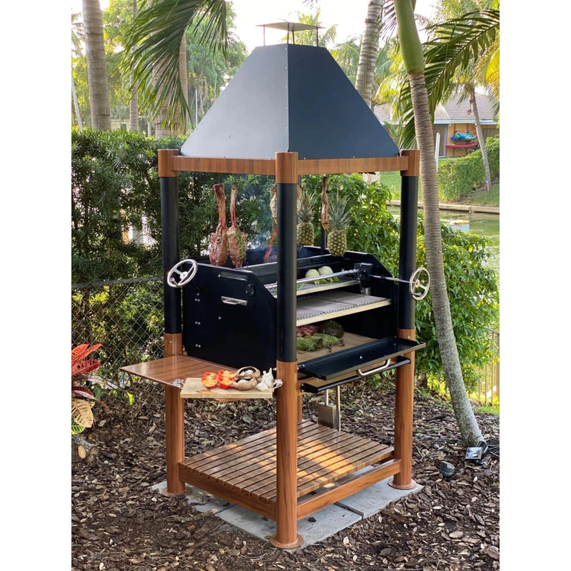 Tagwood BBQ The Beast Argentine Santa Maria grill with black steel body, wooden shelves, height-adjustable grates, and peaked roof.