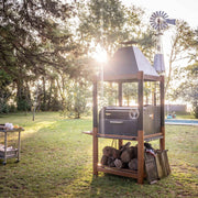 Tagwood BBQ The Beast Argentine Santa Maria Style black steel grill with wood fire brasero and large cooking space outdoors.