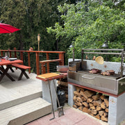 Tagwood BBQ Built-In Santa Maria Argentine wood fire grill in stainless steel with height-adjustable grates and gaucho brasero firebox.