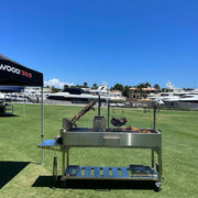 Tagwood BBQ Freestanding Argentine Santa Maria Grill BBQ06SS with stainless steel, height-adjustable grates, brasero firebox, and peaked roof.