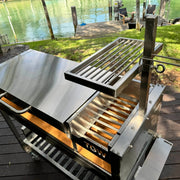 Tagwood BBQ Freestanding Argentine Wood Fire & Charcoal Gaucho Grill BBQ18SS with stainless steel, adjustable grates, and peaked roof for outdoor cooking.