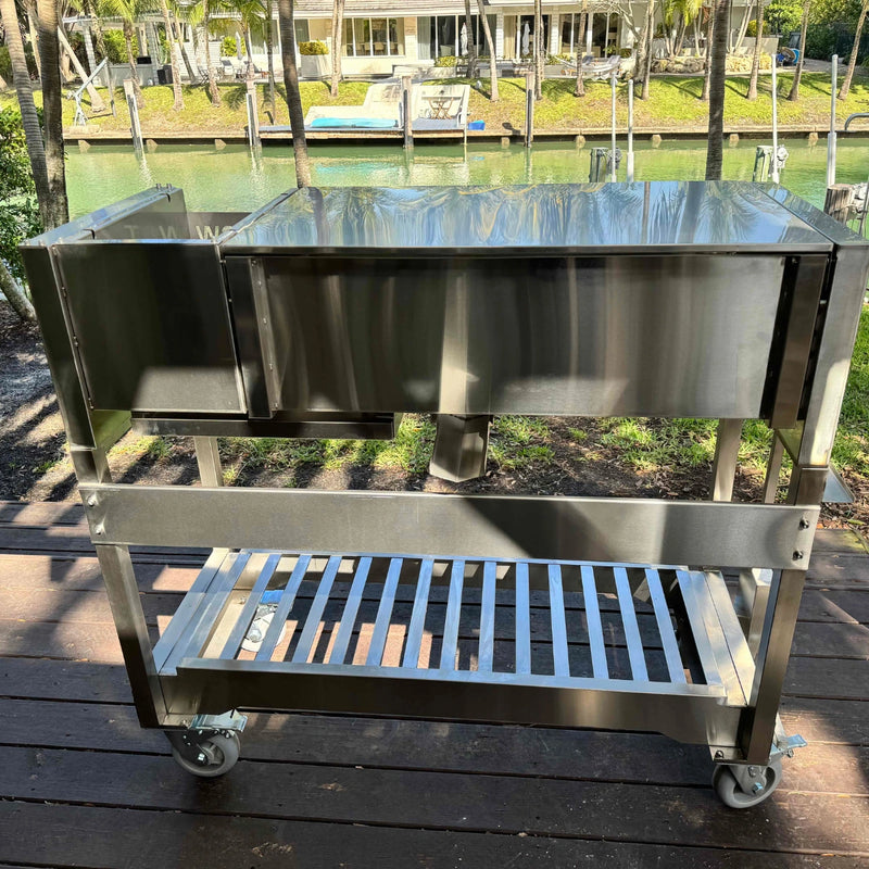 Tagwood BBQ Freestanding Argentine Wood Fire & Charcoal Gaucho Grill BBQ18SS in stainless steel with large cooking area and wheeled base.