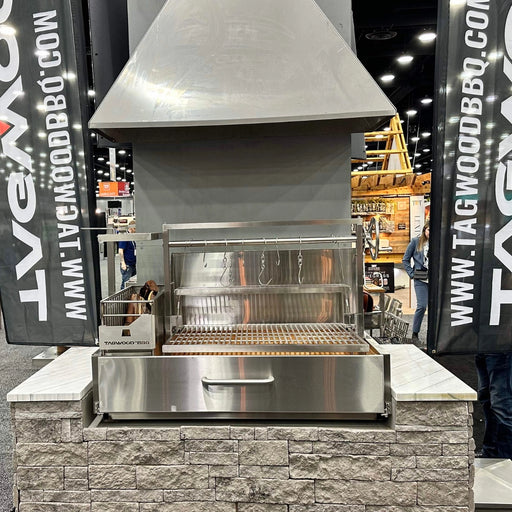 Tagwood BBQ XL Built-In Santa Maria Argentine Wood Fire & Charcoal Gaucho Grill in stainless steel with height-adjustable grates and peaked roof