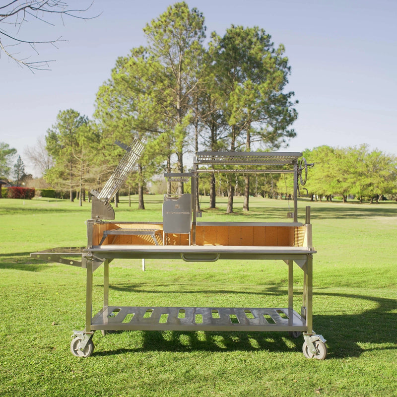 Tagwood BBQ XL Freestanding Argentine Santa Maria Grill with 304 stainless steel, height-adjustable grates, and wheeled cart outdoors.