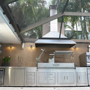 Tagwood BBQ XL Built-In Santa Maria Argentine Grill in stainless steel with large cooking area, height-adjustable grates, and peaked roof.