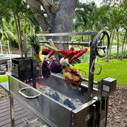Tagwood BBQ Stainless Steel Rotisserie Kit - BBQ50SS with 40-inch stainless steel frame, motor, forks, and clamps roasting meats and vegetables outdoors.