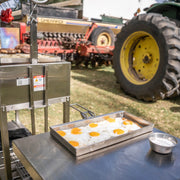 Tagwood BBQ Height Adjustable Griddle - BBQ54SS in stainless steel with adjustable height cooking surface frying eggs outdoors.