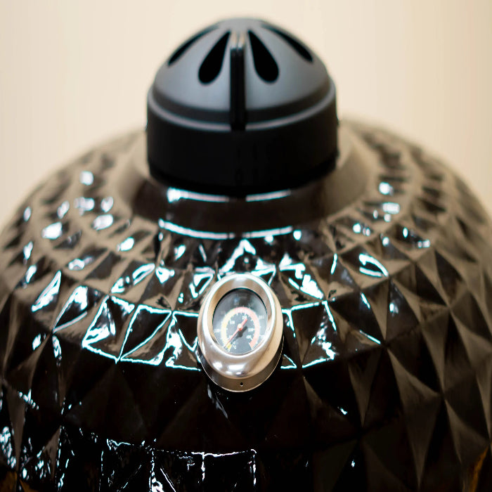 Black ceramic pot with geometric design and central knob on a beige background