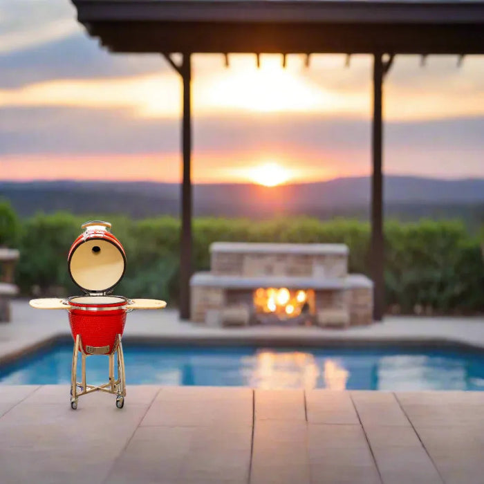 Red barbecue grill on a patio with a pool and sunset in the background