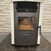 Stovetop oven with glass door on a tiled floor against a stone wall.