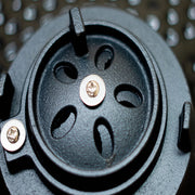 Close-up of a black mechanical component with screws on a metallic background