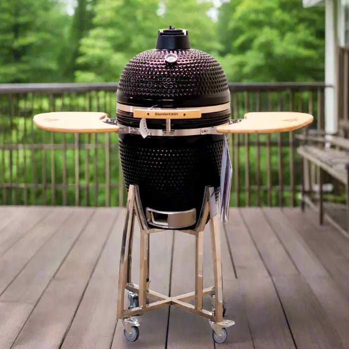 Black Kamado-style grill on a stand with wooden tables on a wooden deck