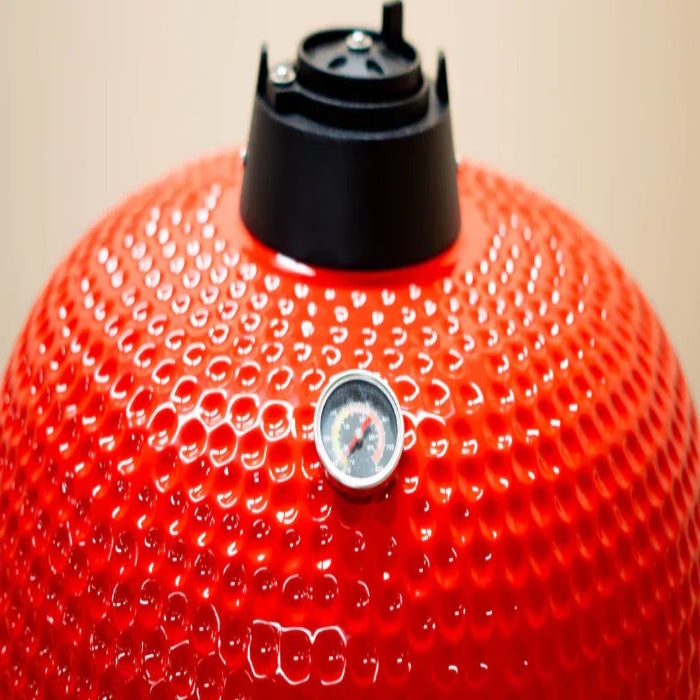 Red barbecue grill dome with a thermometer on a beige background