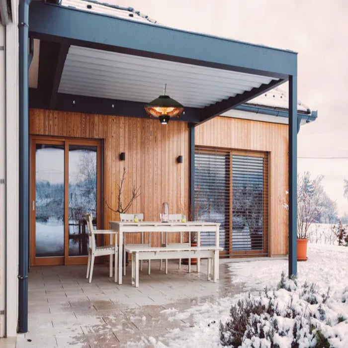 Patio area with a wooden table and chairs in front of a modern house with large windows.