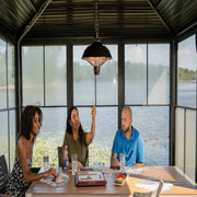 Three people sitting at a table by a large window with a view of water.