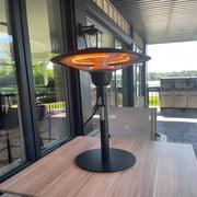 Outdoor patio heater on a table with a view of a building and greenery in the background