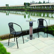 Outdoor patio set with two chairs and a heater table by a body of water.