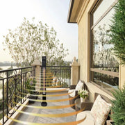 Balcony with outdoor furniture, potted plants, and a view of trees and buildings.