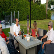 Group of people sitting around a table outdoors, enjoying drinks and food.