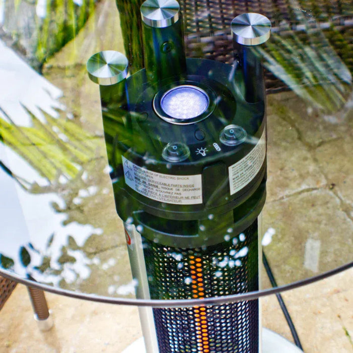 Green bottle with a solar panel on top, placed on a glass table outdoors.
