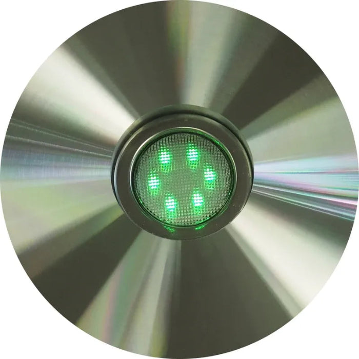 Circular metal object with a green light on a white background