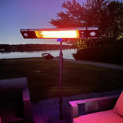 Outdoor patio heater glowing red in a backyard setting with trees and water in the background.