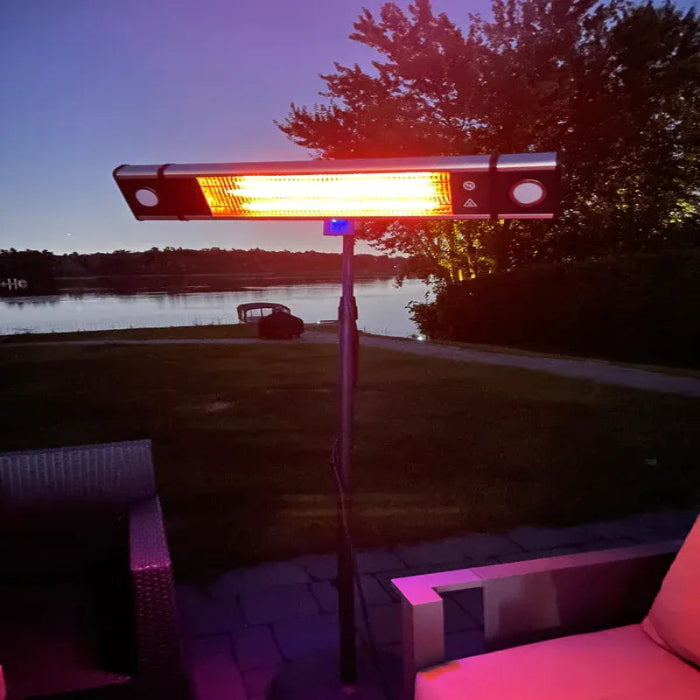 Outdoor patio heater glowing red in a backyard setting with trees and water in the background.