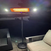 Outdoor patio heater on a patio with chairs by a body of water at night.